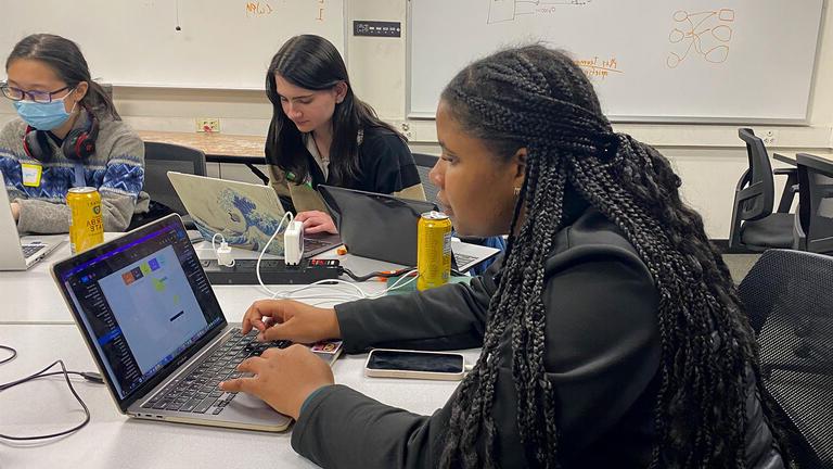 Students work on their laptops at a table